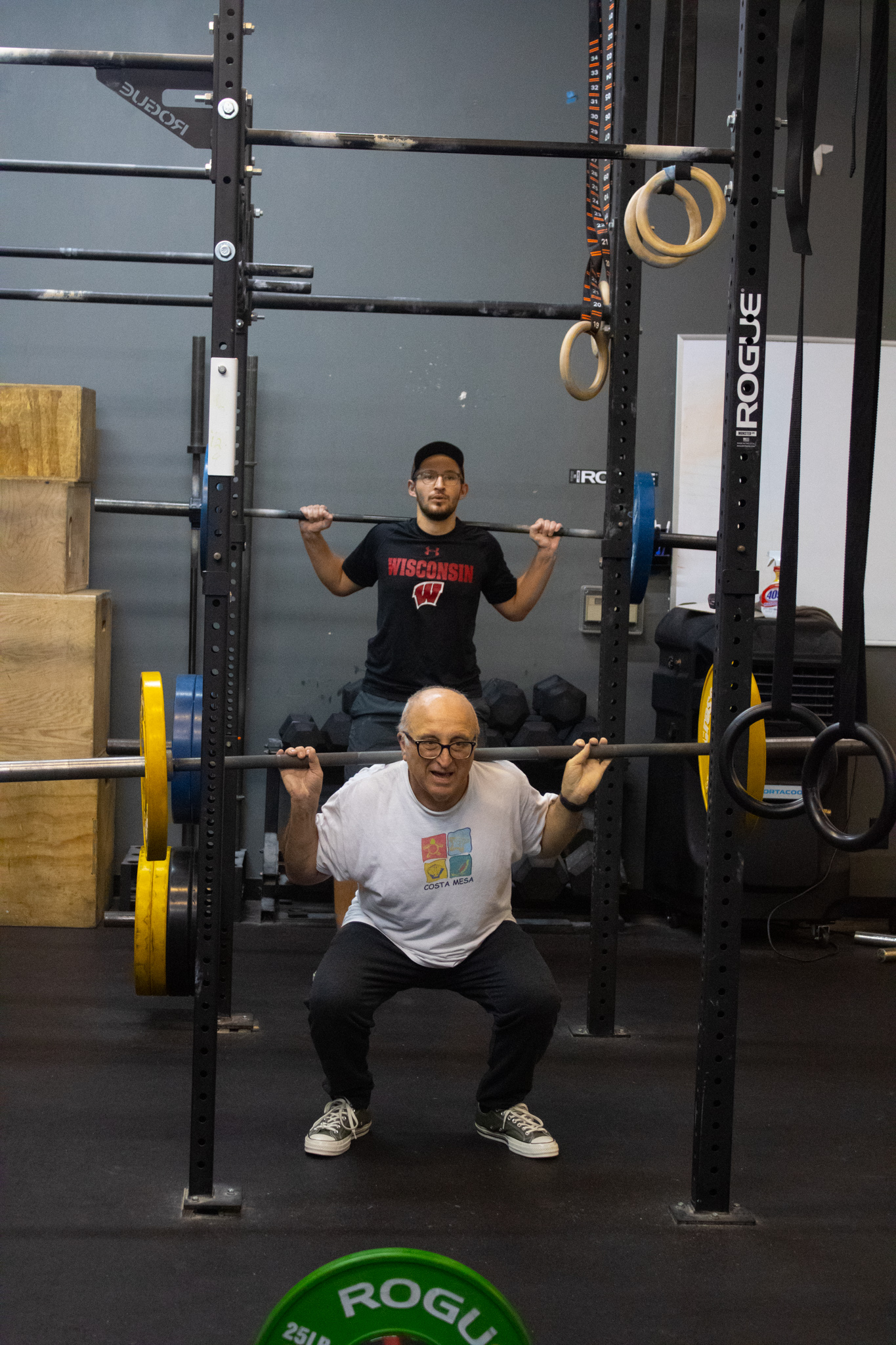 Noah Bloedorn and Roman Lazowski squatting with squat racks at different heights.