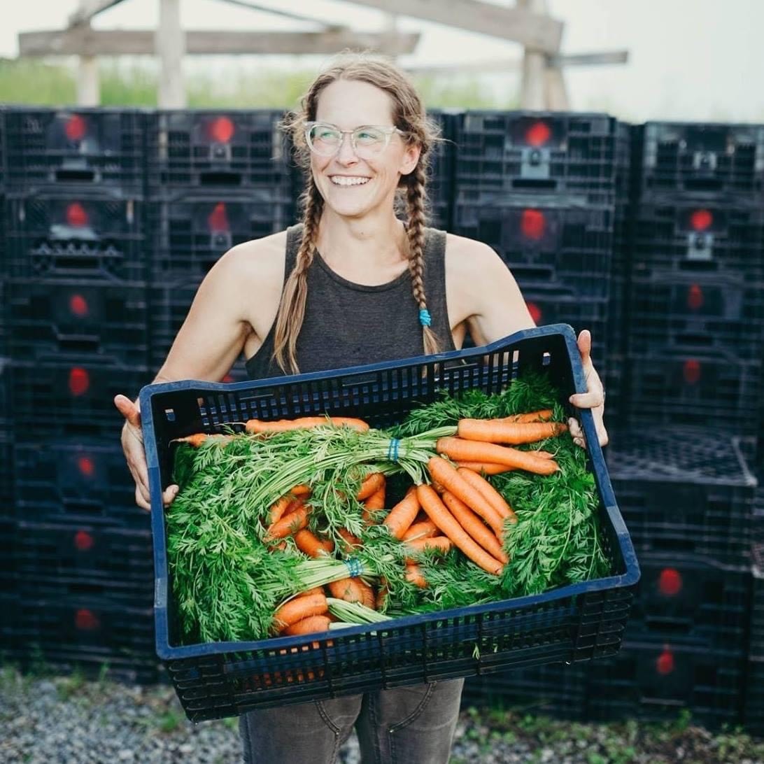 Woman holds a basket of carrots.