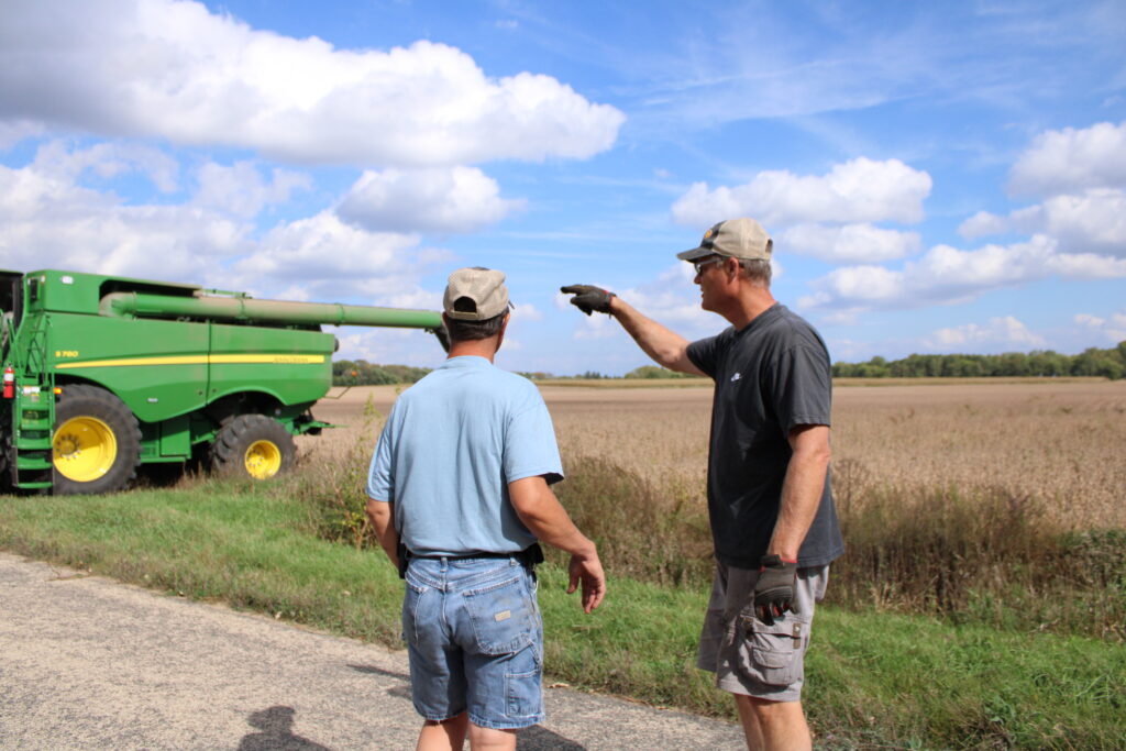 Scott Nelson hands Larry Nelson a rag to clean the combine. Emma Conway photo.