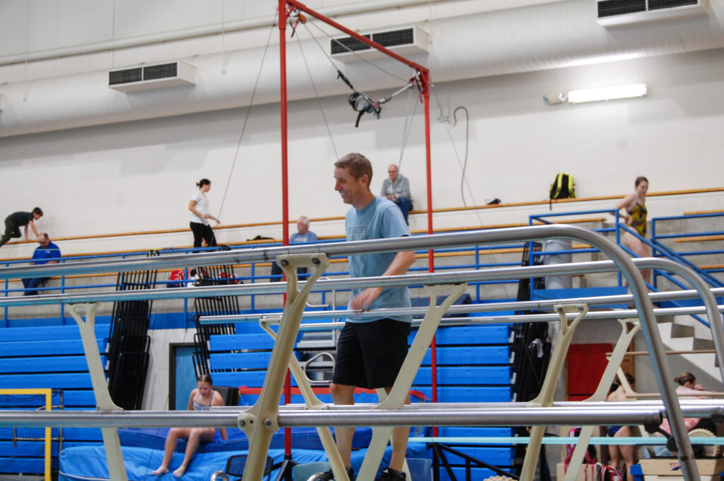 Coach Todd walking around the gym practice area of the aquatic center. 