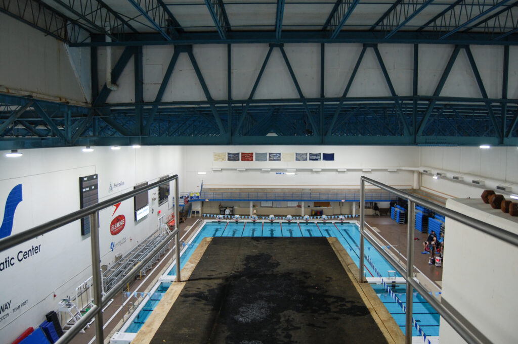 View of the pool from the top of a 10 meter platform, featuring parts of the platform and the pool. 