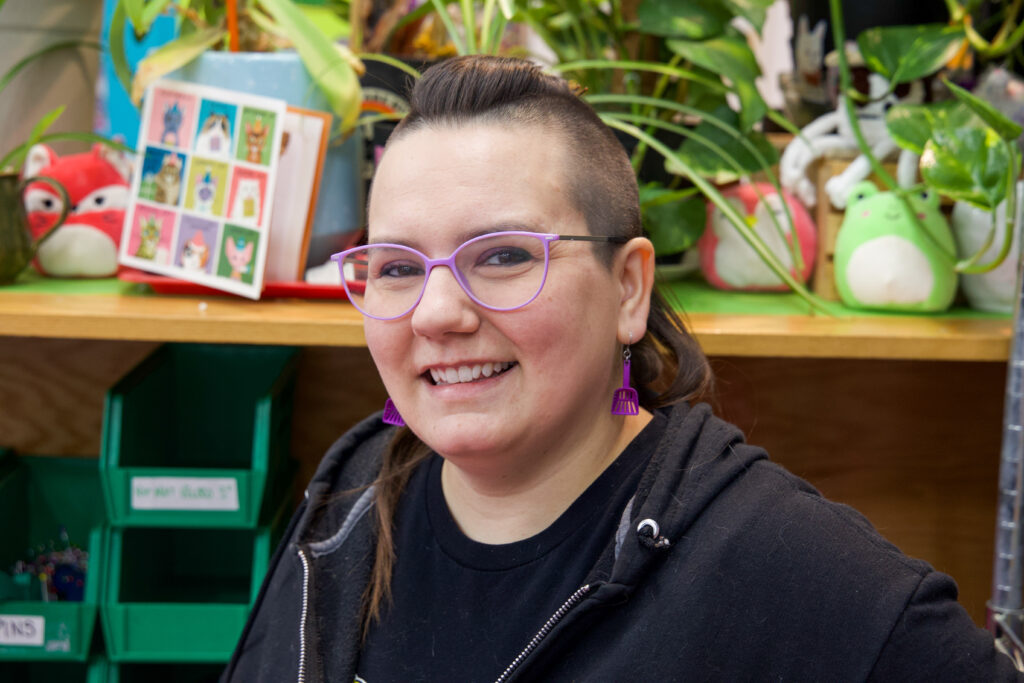 Meagan Porter smiling wearing purple earrings and glasses. 