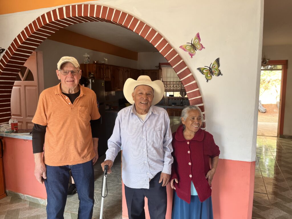 Three people stand in front of a doorway.