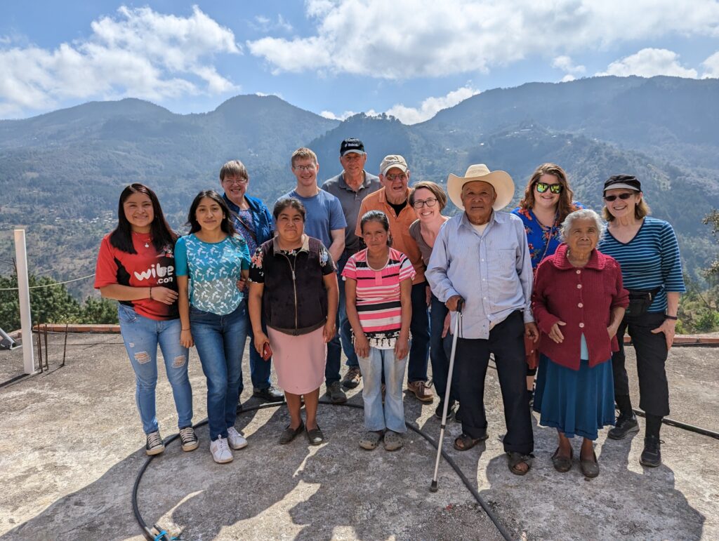 A group of people stands in front of a mountain range.