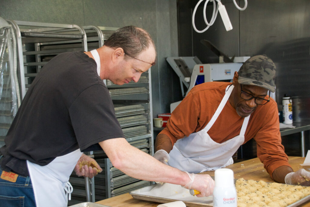 Two bakers working together to lay out cookies. 