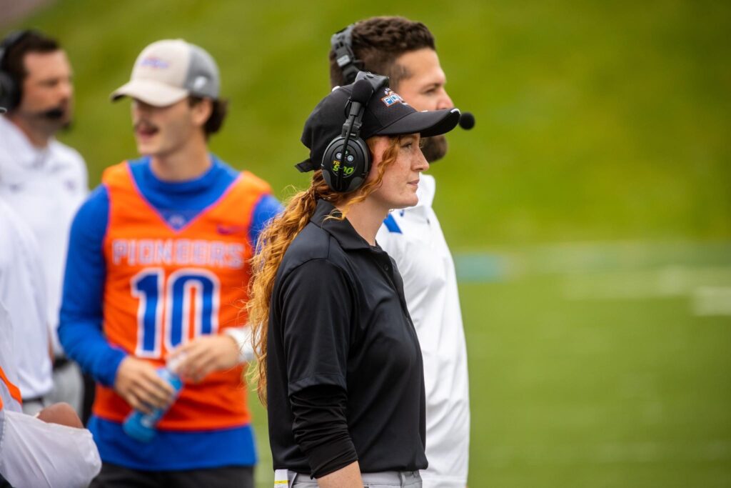 Women looking out onto a football field with headphones on. 