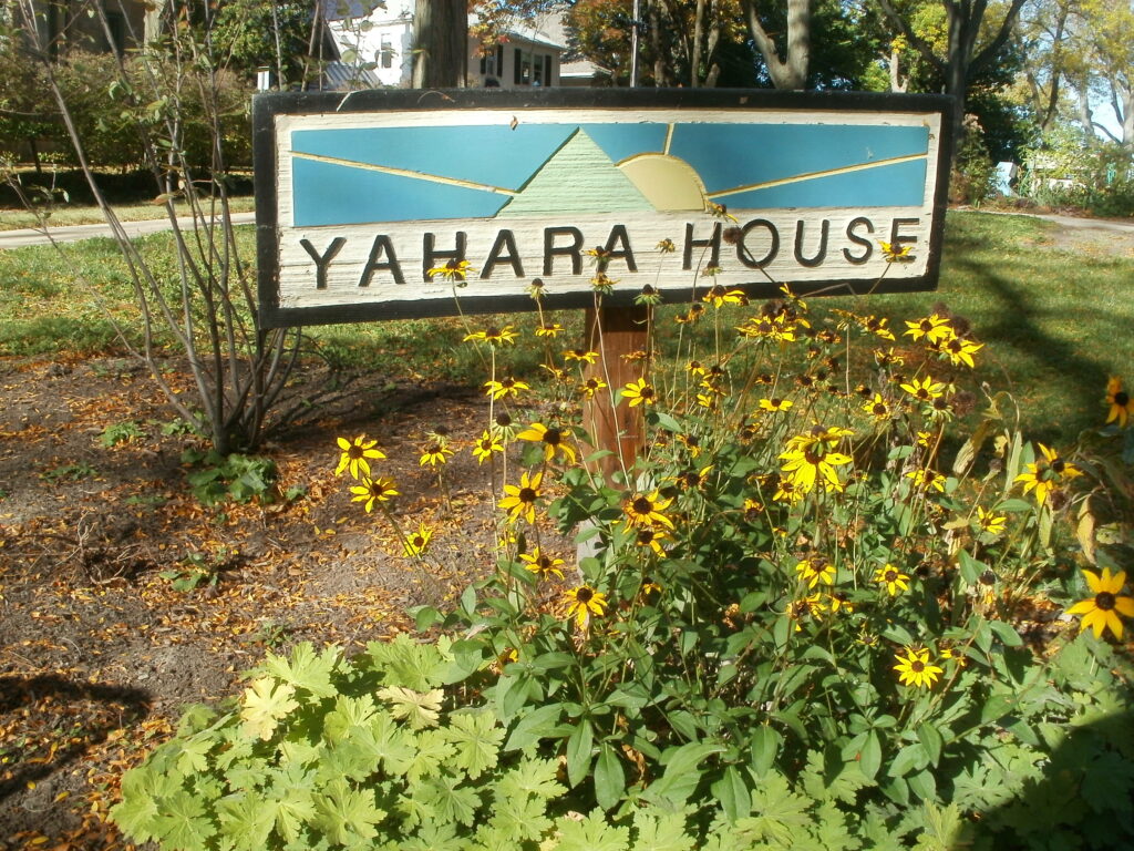 Yahara House sign sits among yellow flowers