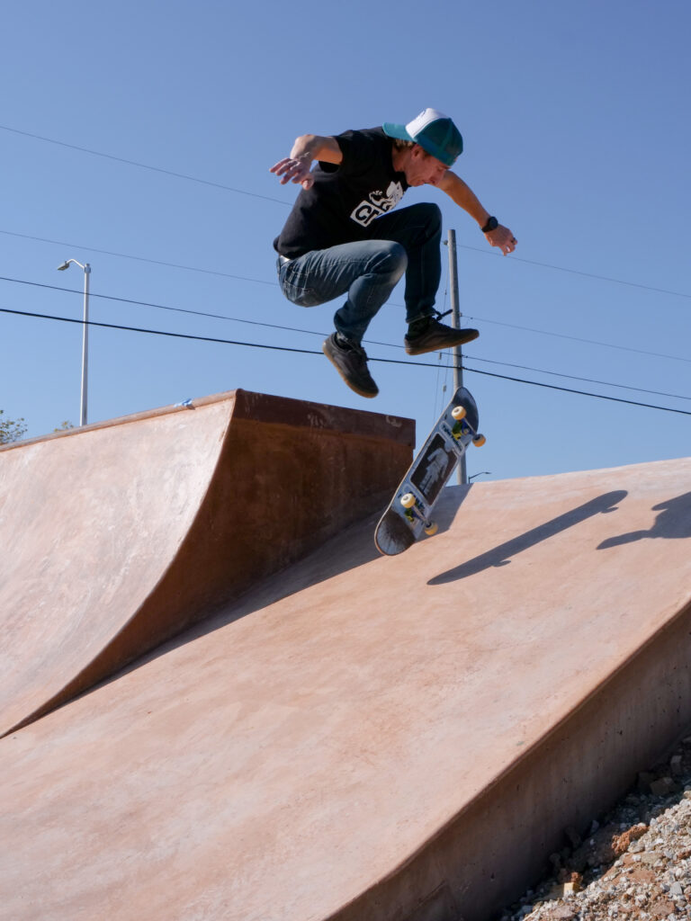 Man doing a kick flip of a ramp.