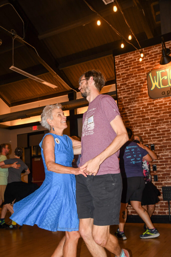 Nick Bryan swings partner Judy Selp. Selp wears a blue dress that spins.