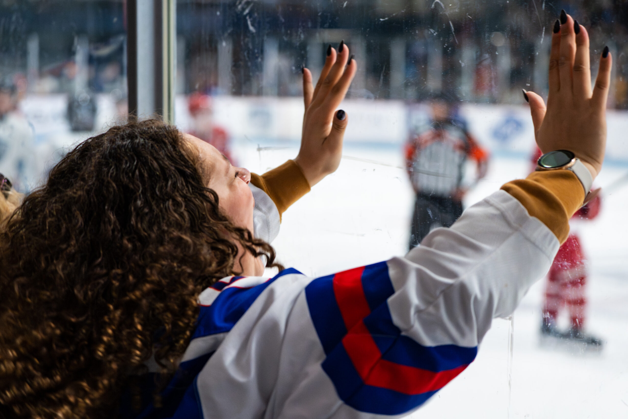 Hockey fan yelling with her hands on the glass.