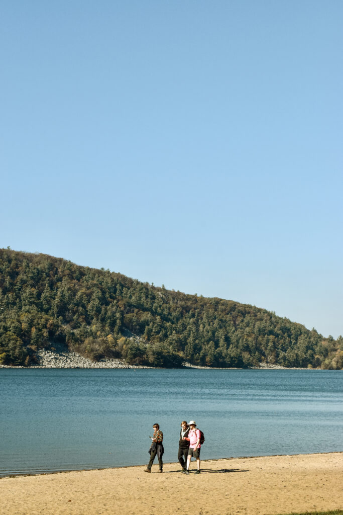 Three hikers walk on the edge of a lake.