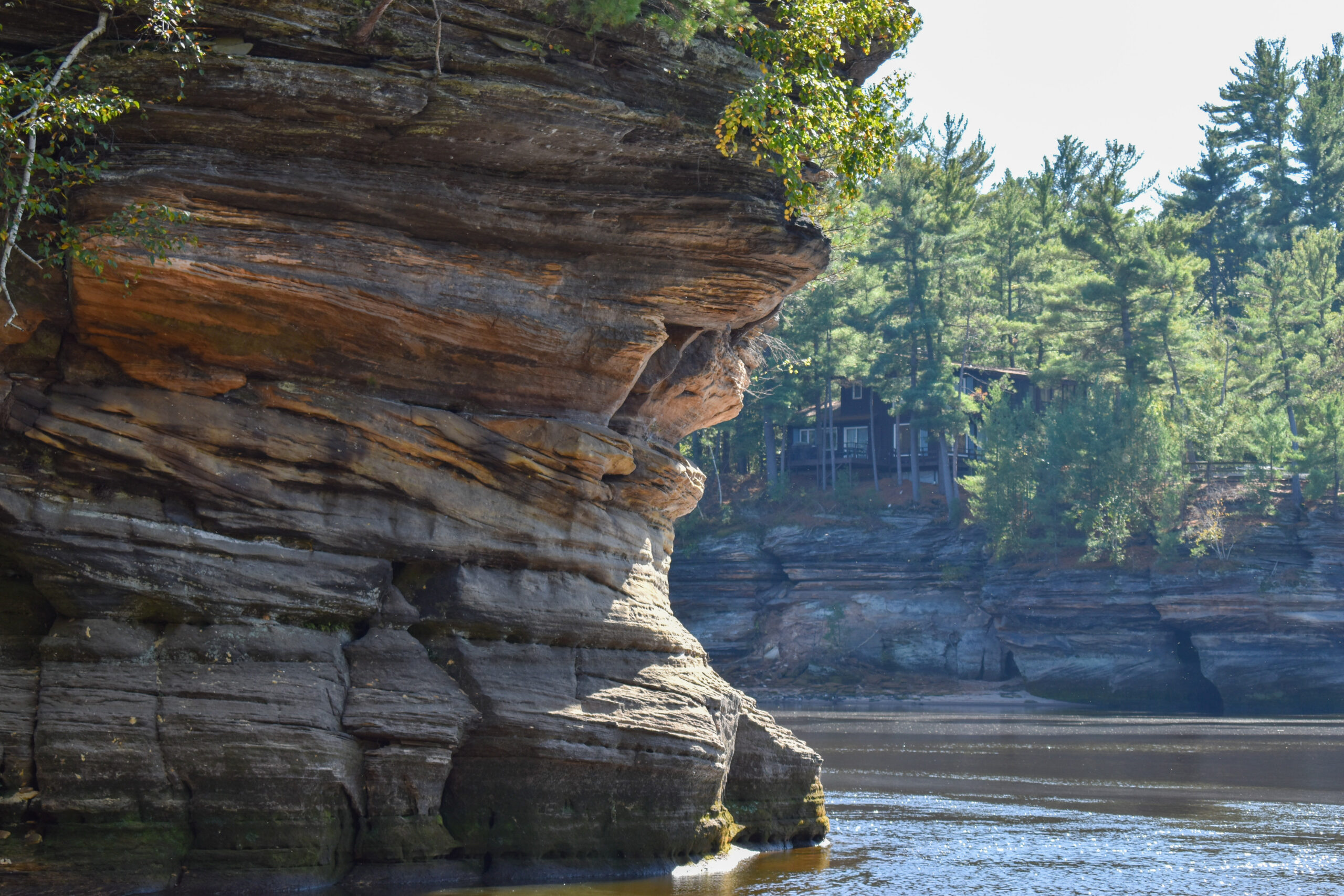 A layered natural rock bordering a body of water.