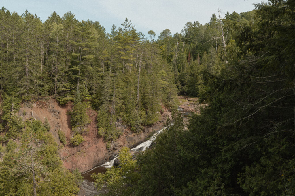 waterfall peaks through the trees in the woods