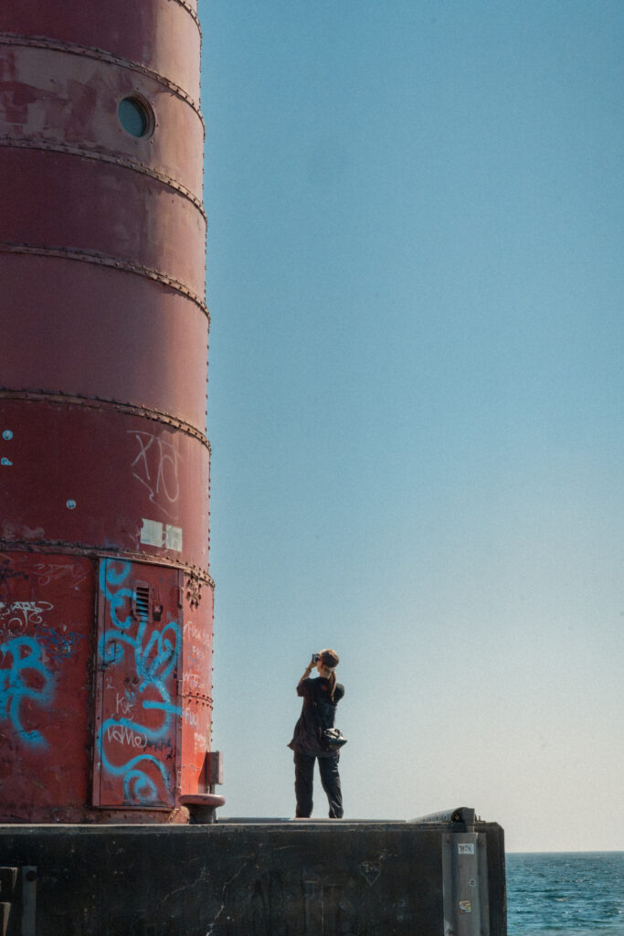 woman takes a picture of a tall red structure