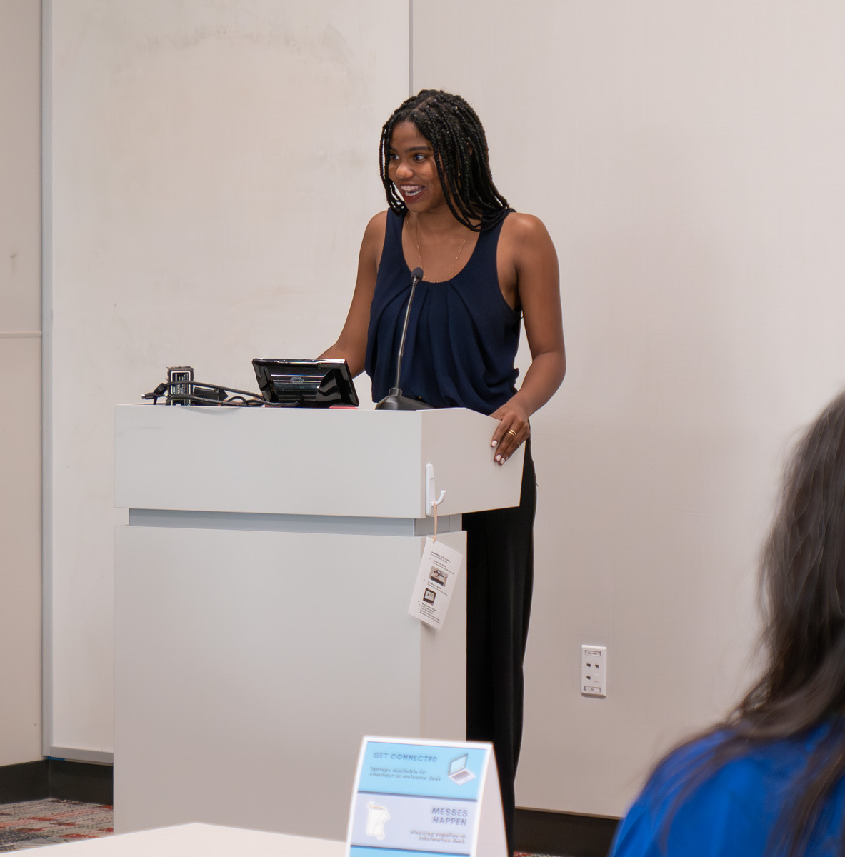 Maliha Nu’Man speaks at a podium.