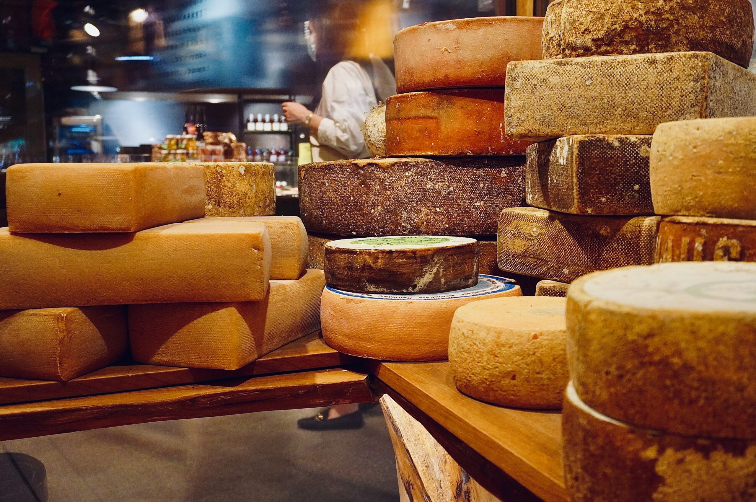 Large selection of cheese displayed on wooden boards.
